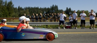 Two participants in Saturday's Sammamish Challenge Day Race approach the finish line as Skyline cheerleaders and football players root them on.